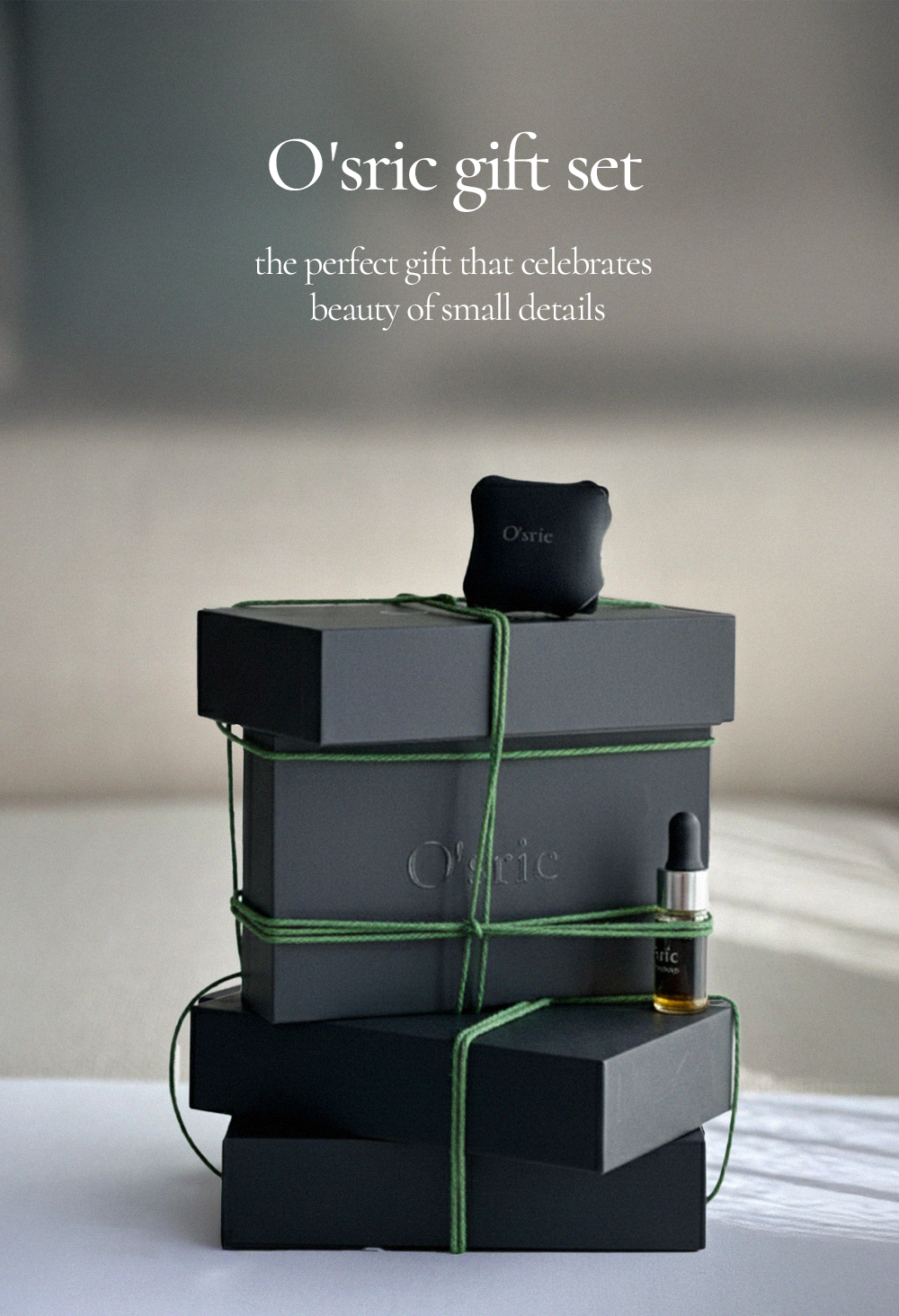 O'sric gift set with black boxes tied with green ribbons on a light surface.